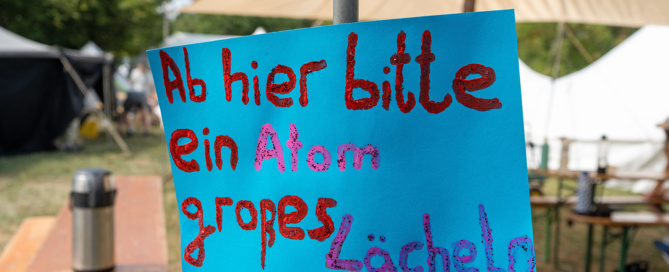 Ein Papierschild mit der Aufschrift «Ab hier bitte ein atomgroßes Lächeln!»